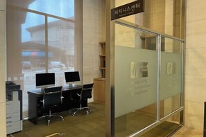 Un espace d’accueil d’hôtel doté d’une cloison en verre, de deux écrans d’ordinateur et d’un panneau indiquant l’emplacement du centre d’affaires.