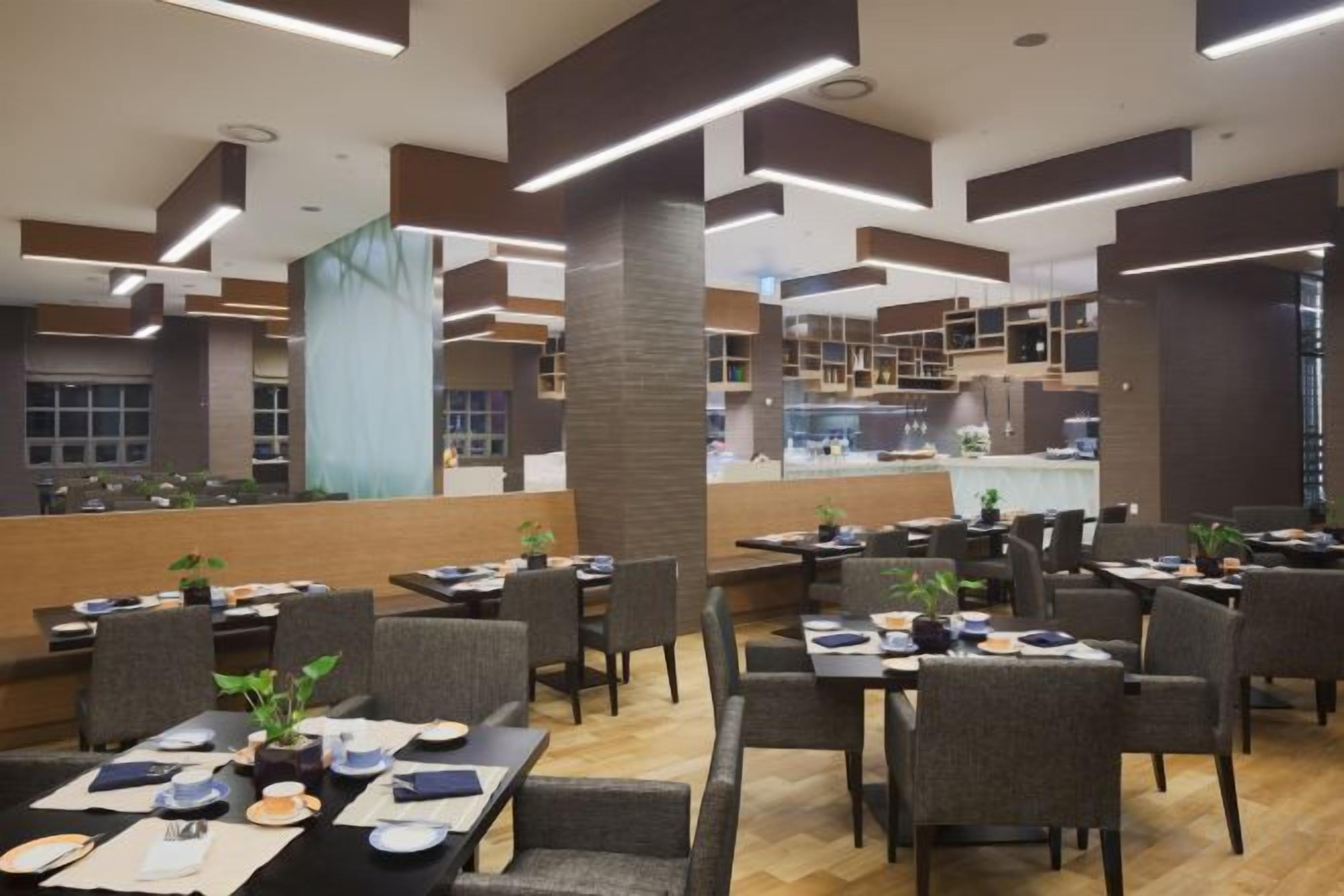 A modern restaurant with high ceilings, multiple dining areas, and a view of the kitchen in the background.