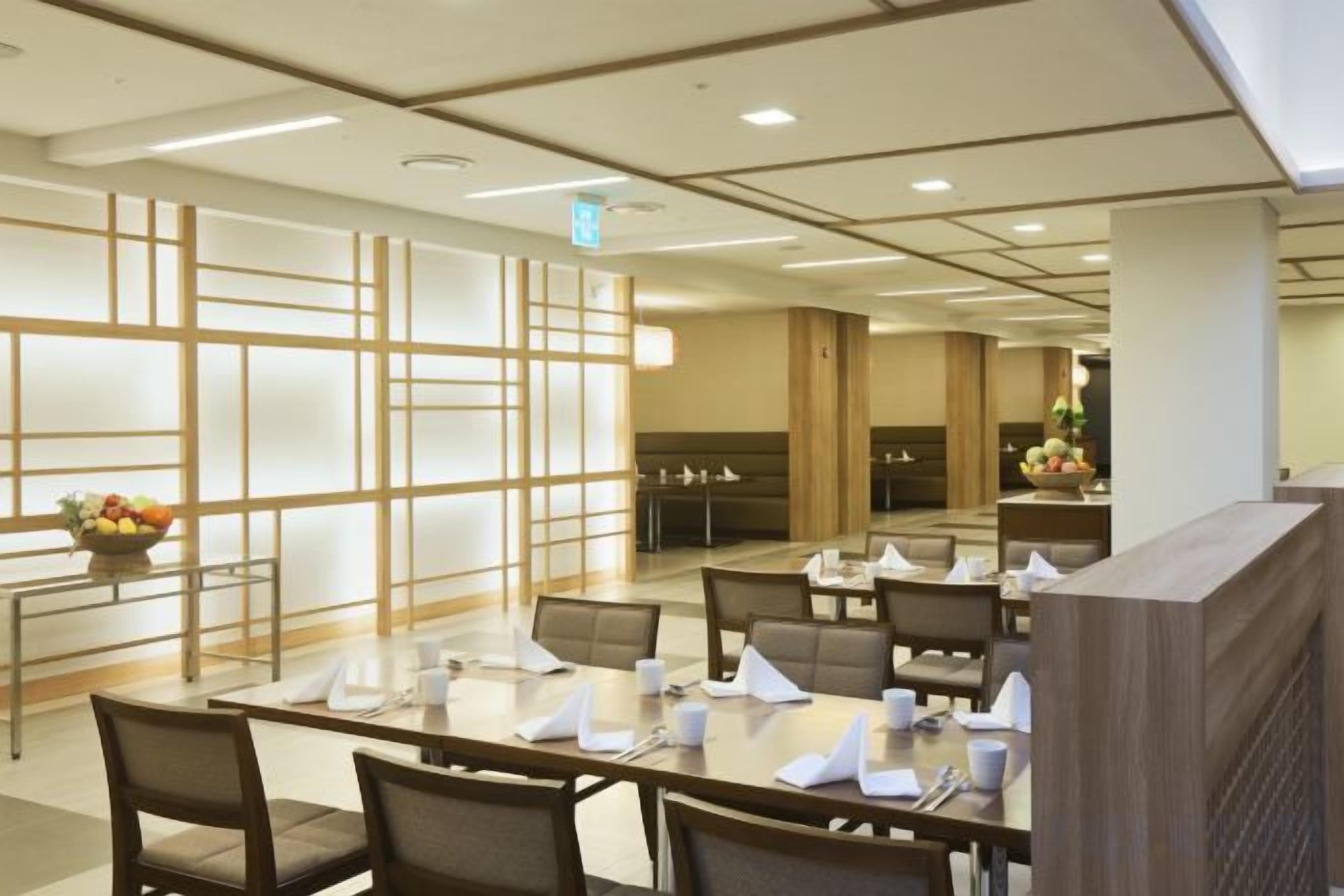 A hotel dining area with multiple tables, chairs, and a decorative wall with a geometric pattern.