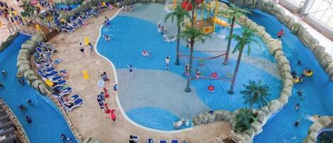 Een overdekt waterpark met verschillende zwembaden, glijbanen en ontspanningszones.