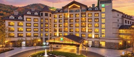 Un hotel grande con varios pisos, un patio central e ingreso bien iluminado.