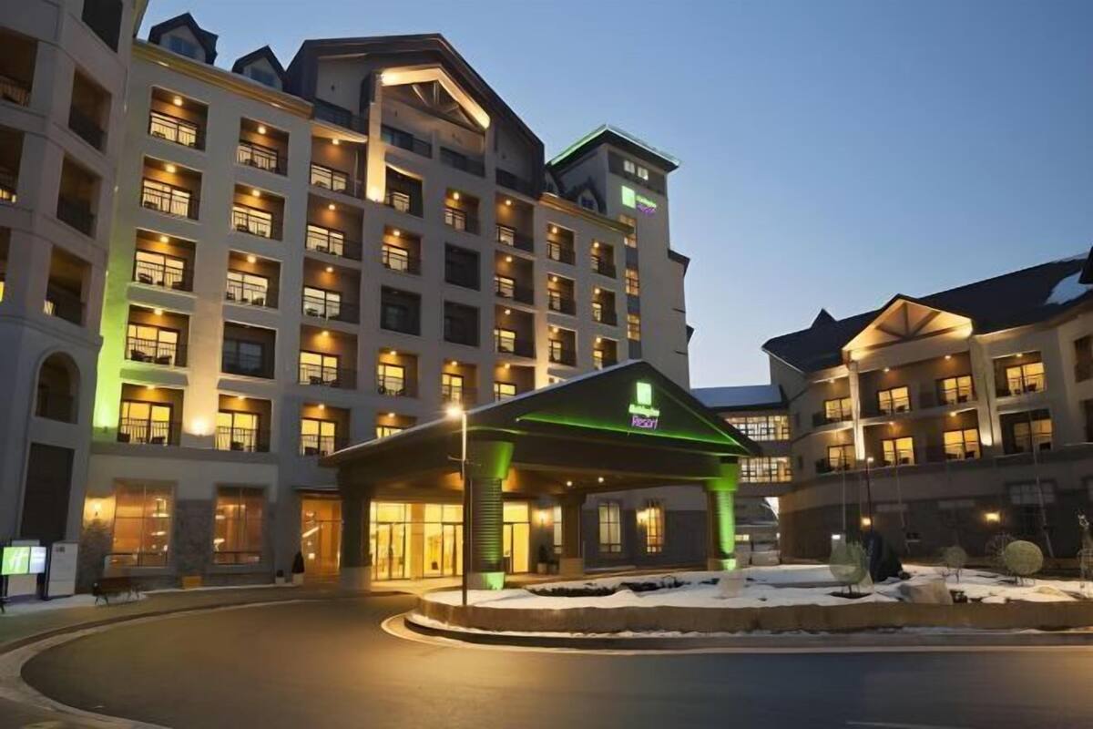 Een meerlaags hotel met een centrale ingang en een overdekt gedeelte.