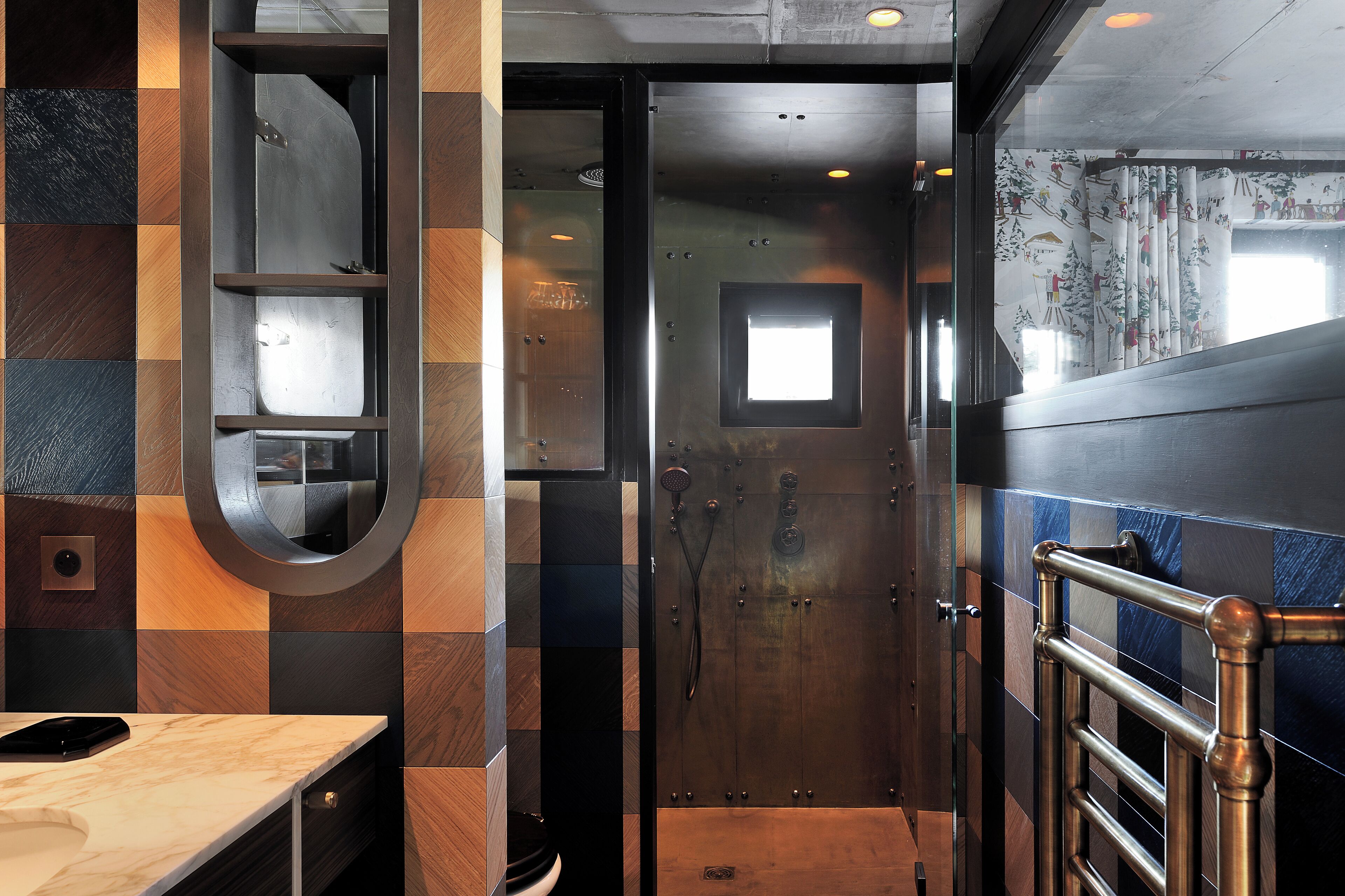 A bathroom with a checkered tile wall, a mirror, a towel rack, and a shower area.