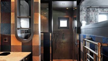 A bathroom with a checkered tile wall, a mirror, a towel rack, and a shower area.
