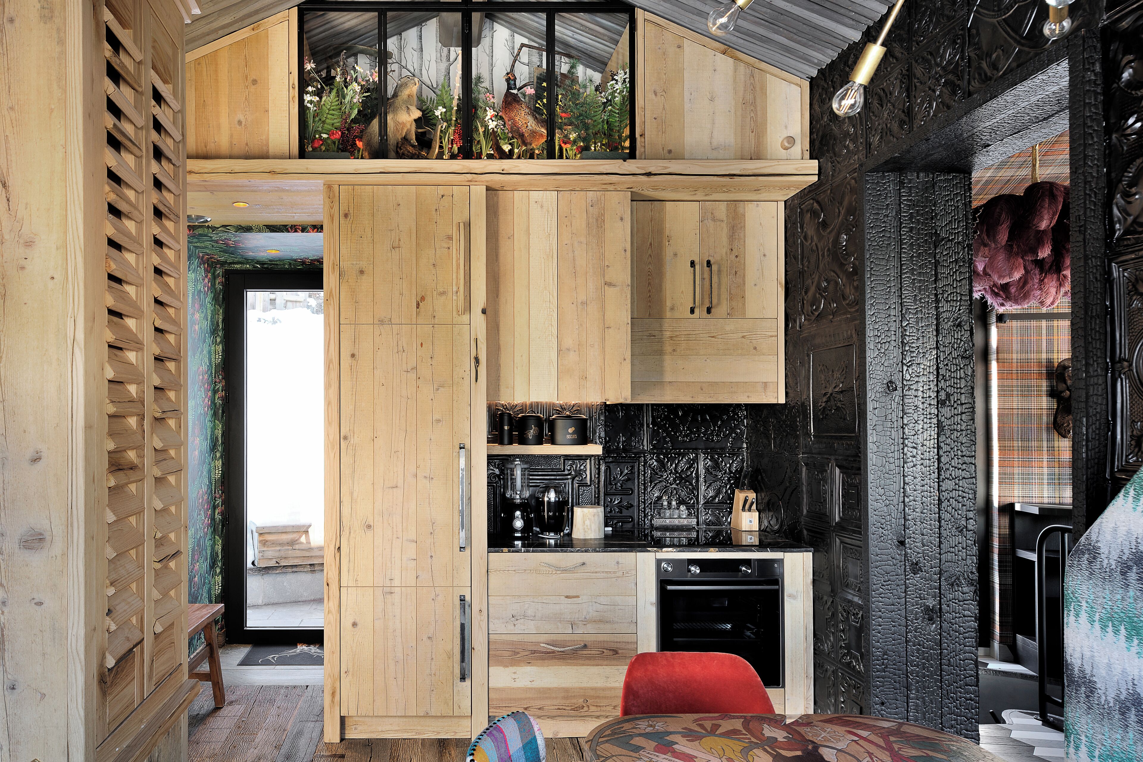 A compact kitchen with wooden cabinetry, a black countertop, and a visible stove.
