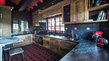 A modern kitchen with wooden cabinets, a red patterned floor, and a large window.