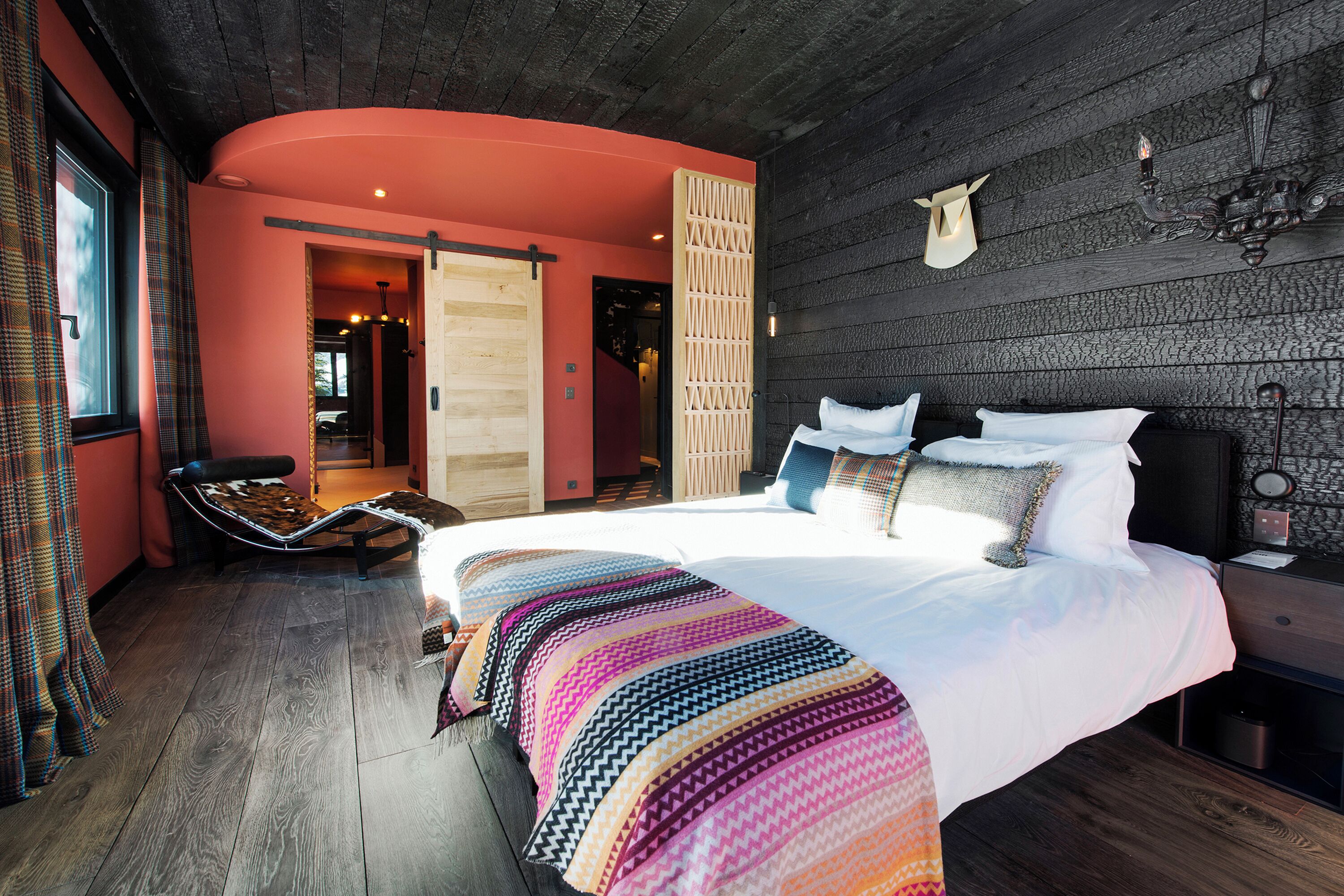 Un dormitorio con una cama grande, piso de madera y vista a un pasillo.