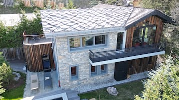 Una casa moderna de dos pisos con fachada de piedra, un balcón y una piscina.