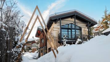 Un bâtiment en bois, doté d’un toit en pente et de grandes fenêtres, entouré de neige.