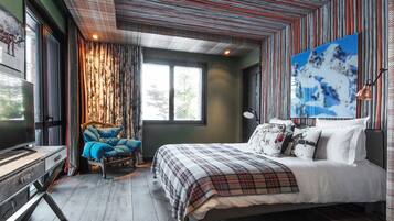 A bedroom with a bed, a chair, a desk, and a large window.