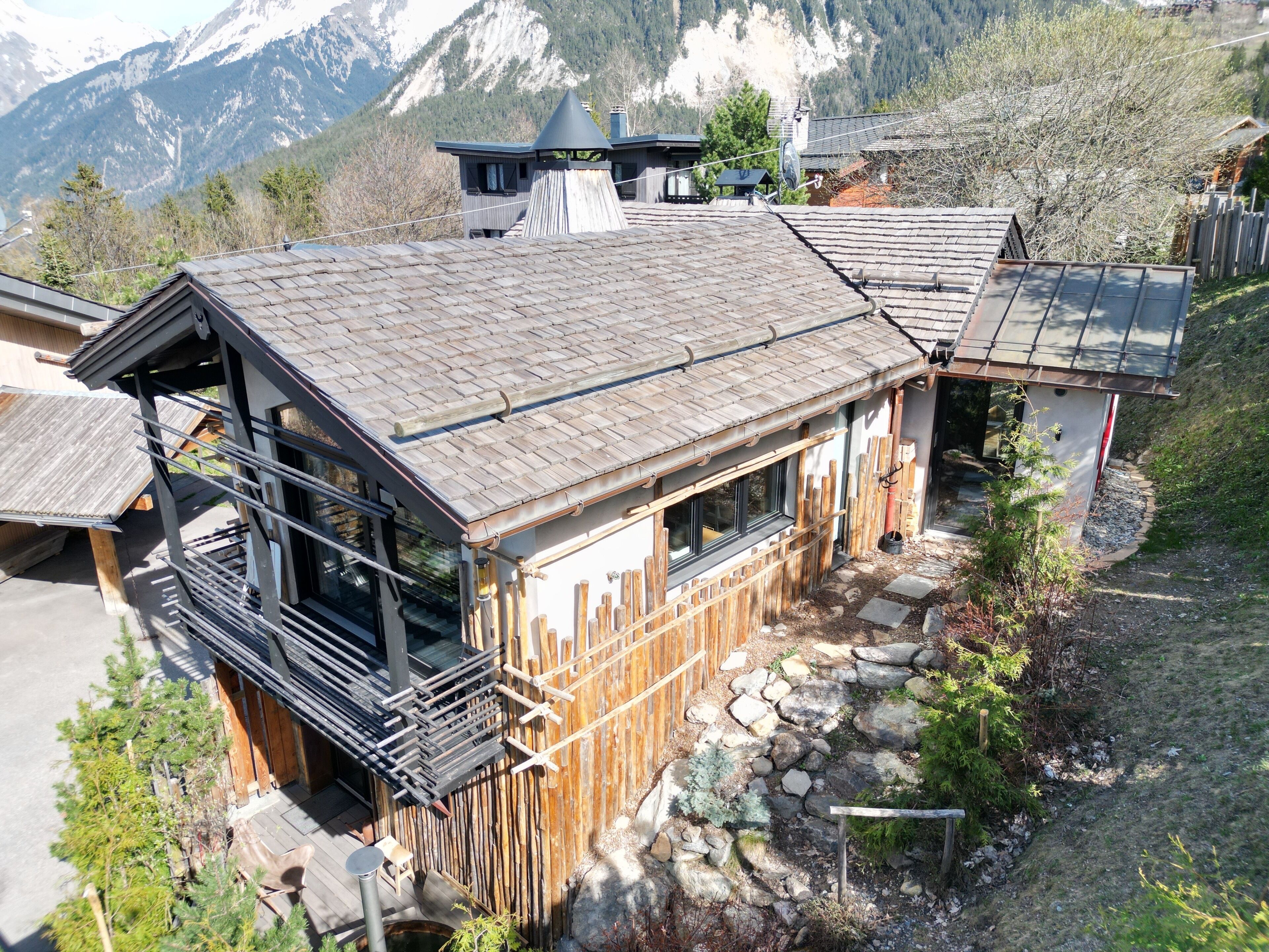 A wooden cabin with a sloped roof, a balcony, and a stone pathway leading to the entrance.