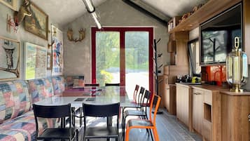 Ett modernt kök med en stor TV, träskåp och en matplats med bord och stolar.