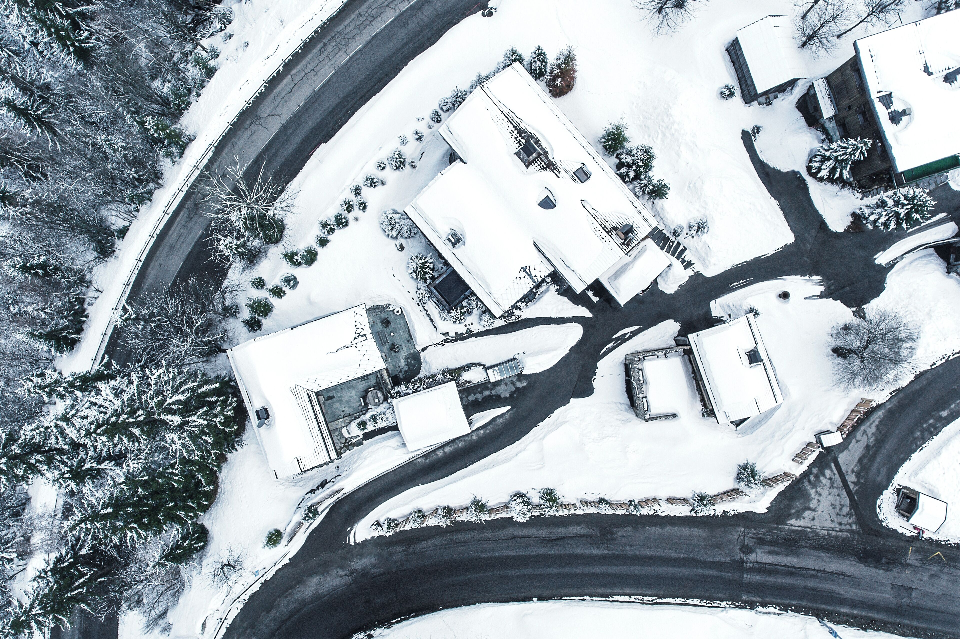 An aerial view of a snow-covered area with buildings, roads, and trees.