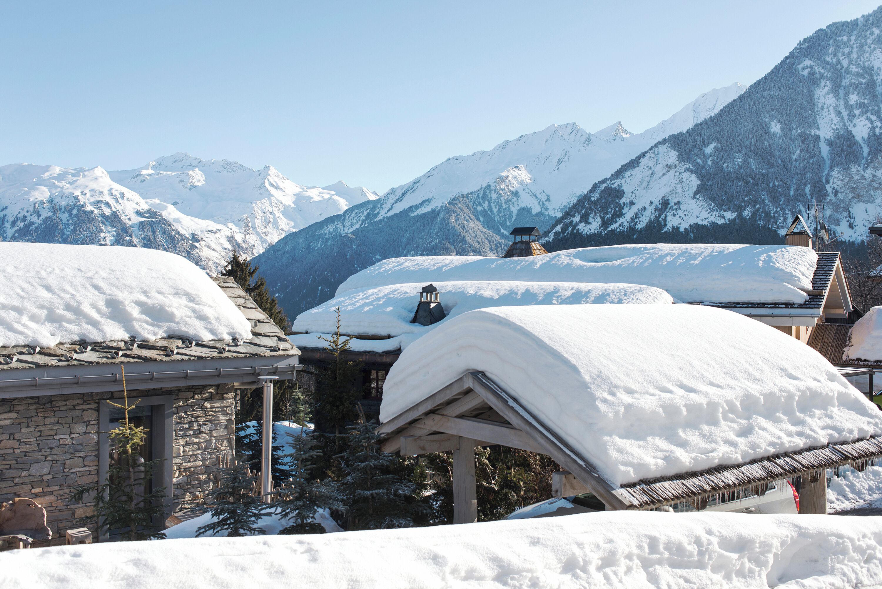 A snow-covered mountain village with traditional wooden houses and a stone building.