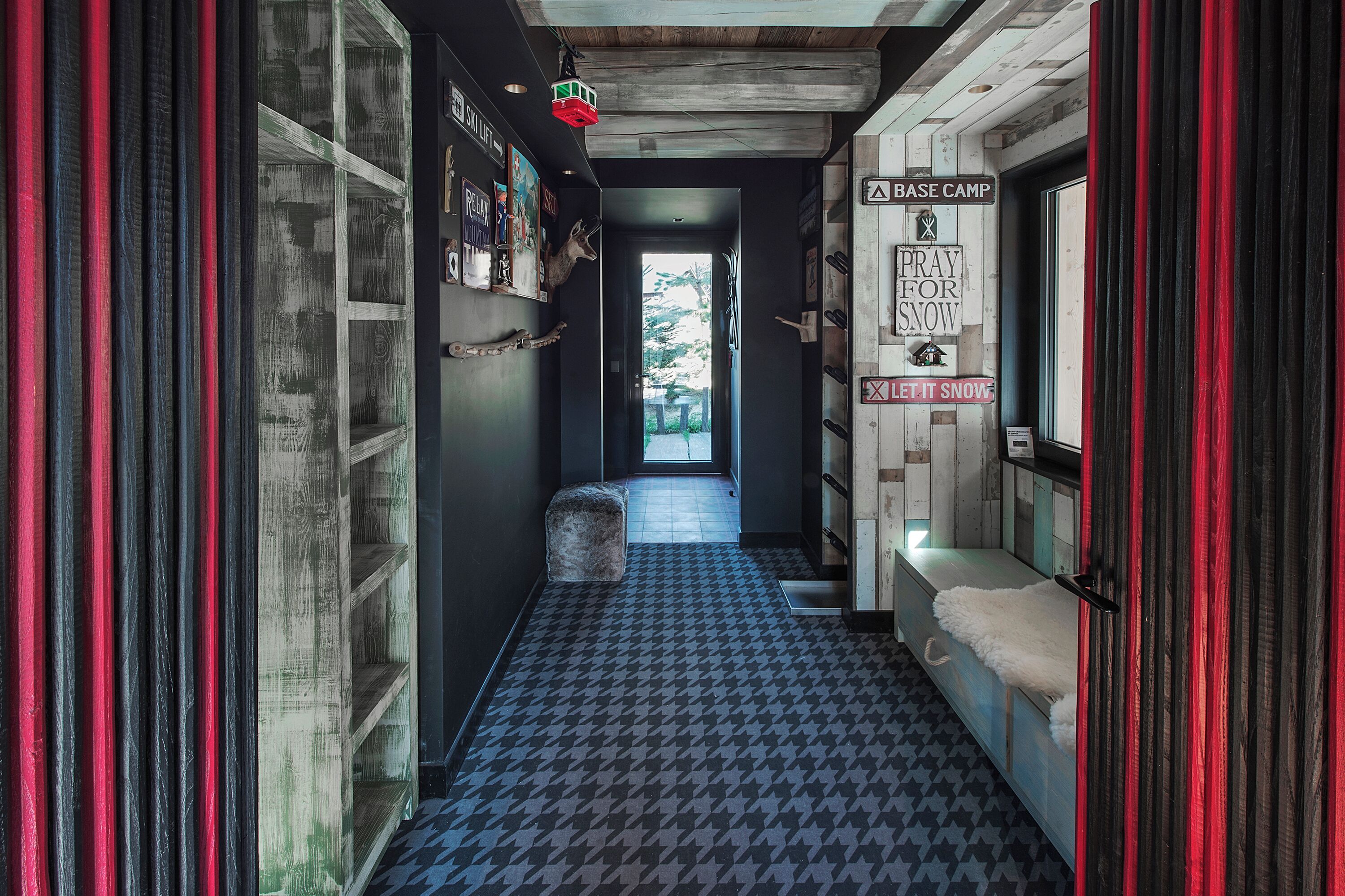 A narrow hallway with patterned flooring, a bench with a fur throw, and a door leading to a room labeled "BASE CAMP."