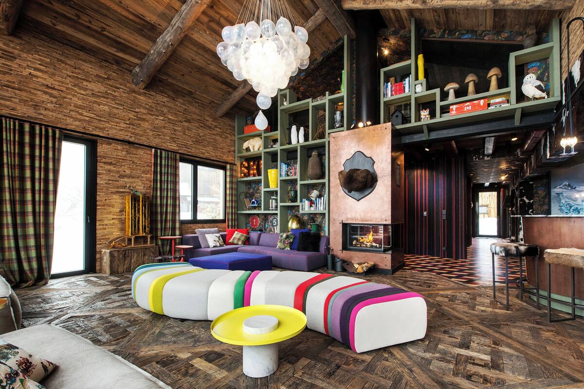 Una sala moderna con un amplio sofá modular, una chimenea y un techo de madera.