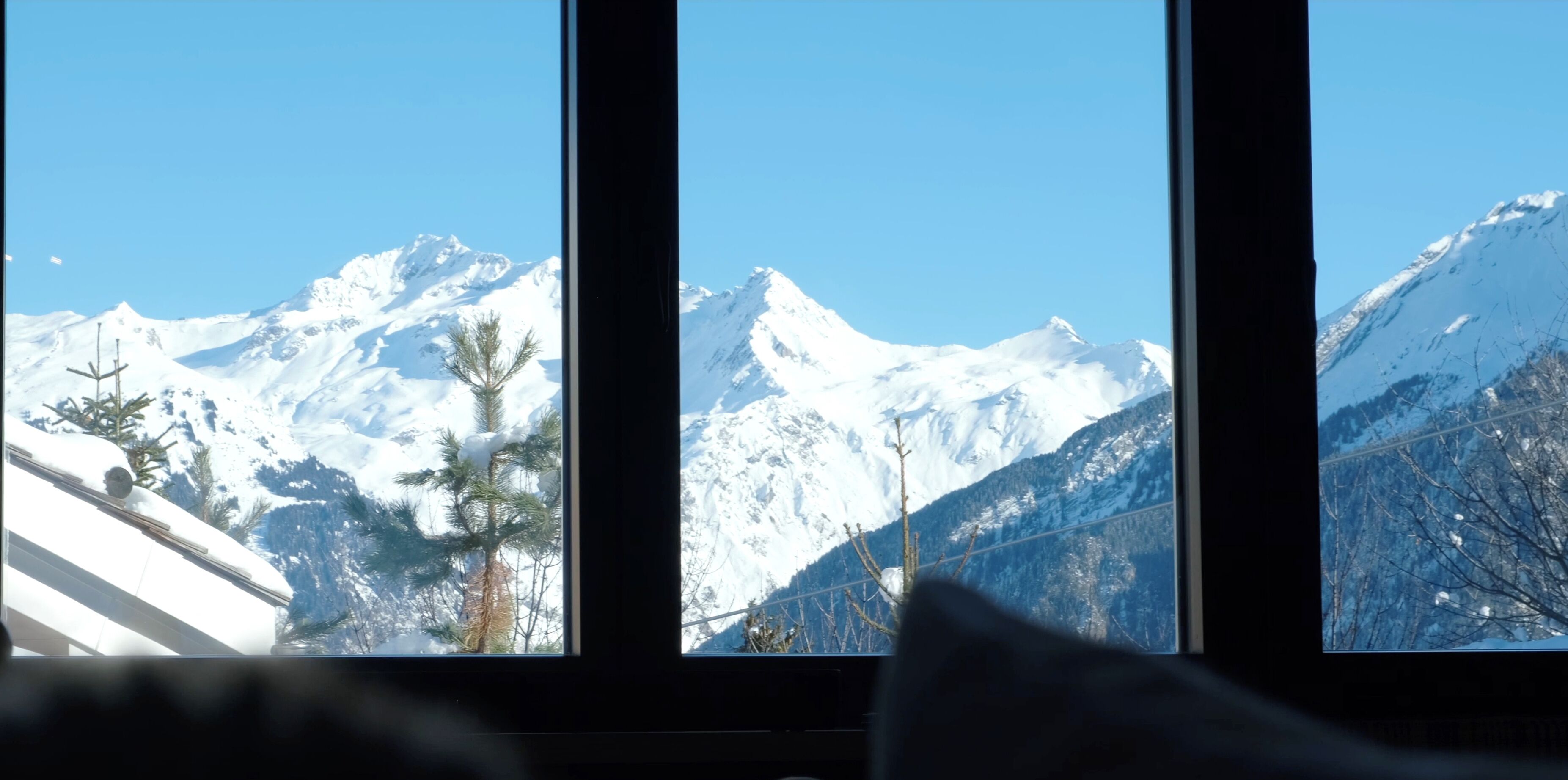 Una habitación con un amplio ventanal que ofrece vistas a montañas nevadas.