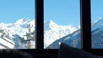 Una habitación con un amplio ventanal que ofrece vistas a montañas nevadas.