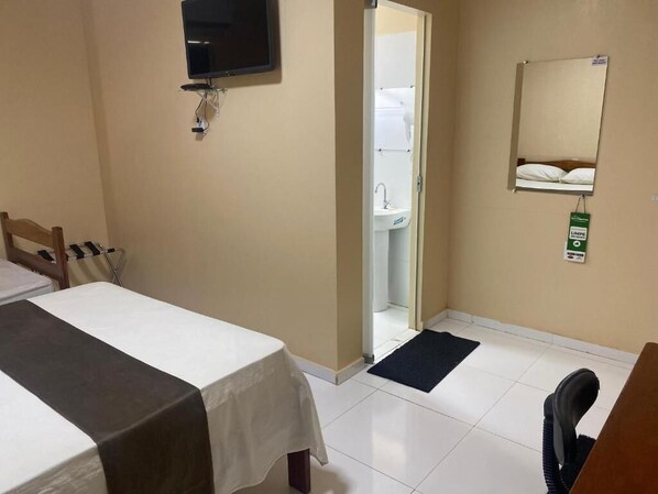 Una habitación de hotel con dos camas, televisión, baño con lavamanos y espejo.