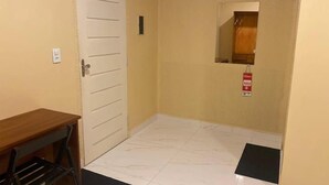A hallway with a white door, a small table, and a mirror on the wall.