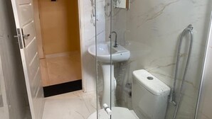A bathroom with a glass shower enclosure, a sink, and a toilet.