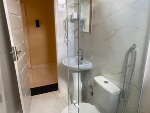 Baño con cabina de ducha de vidrio, lavabo e inodoro.