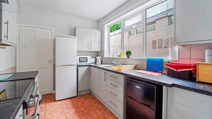 A modern kitchen with white cabinets, a black countertop, and a red tiled floor. - Spacious 4‑Bed Home • WV1 • Family & Contractor Friendly (Wolverhampton)