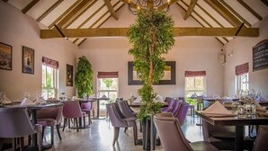 A restaurant with wooden beams, tables set with wine glasses, and large potted plants. - Spacious 4‑Bed Home • WV1 • Family & Contractor Friendly (Wolverhampton)