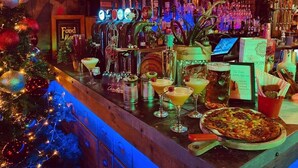 A bar area with a Christmas tree, various bottles, and a pizza on the counter. - Spacious 4‑Bed Home • WV1 • Family & Contractor Friendly (Wolverhampton)
