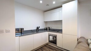 A modern kitchen with white cabinets, a black countertop, a built-in oven, and a sink.