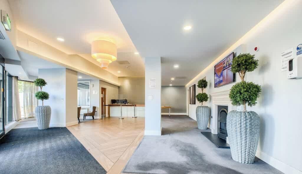 A hotel lobby with a reception desk, seating area, and a fireplace.