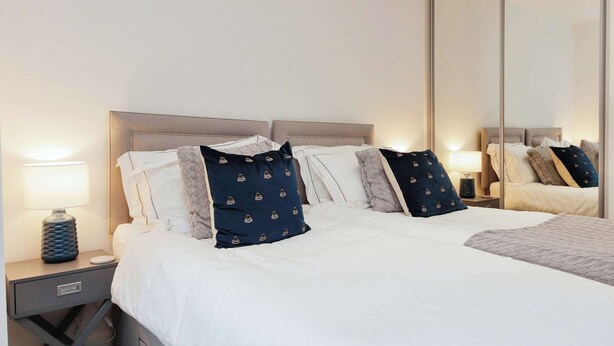 A neatly made bed with a headboard, a bedside lamp, and a mirror. - Central Solihull 1-Bed | Parking • WiFi • NEC (Solihull)