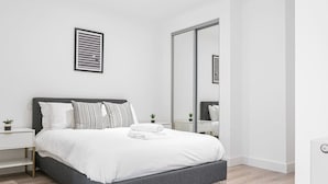 A modern bedroom with a grey bed, white bedding, and a large mirror. - Solihull Studio • WiFi • NEC • BHX (Solihull)