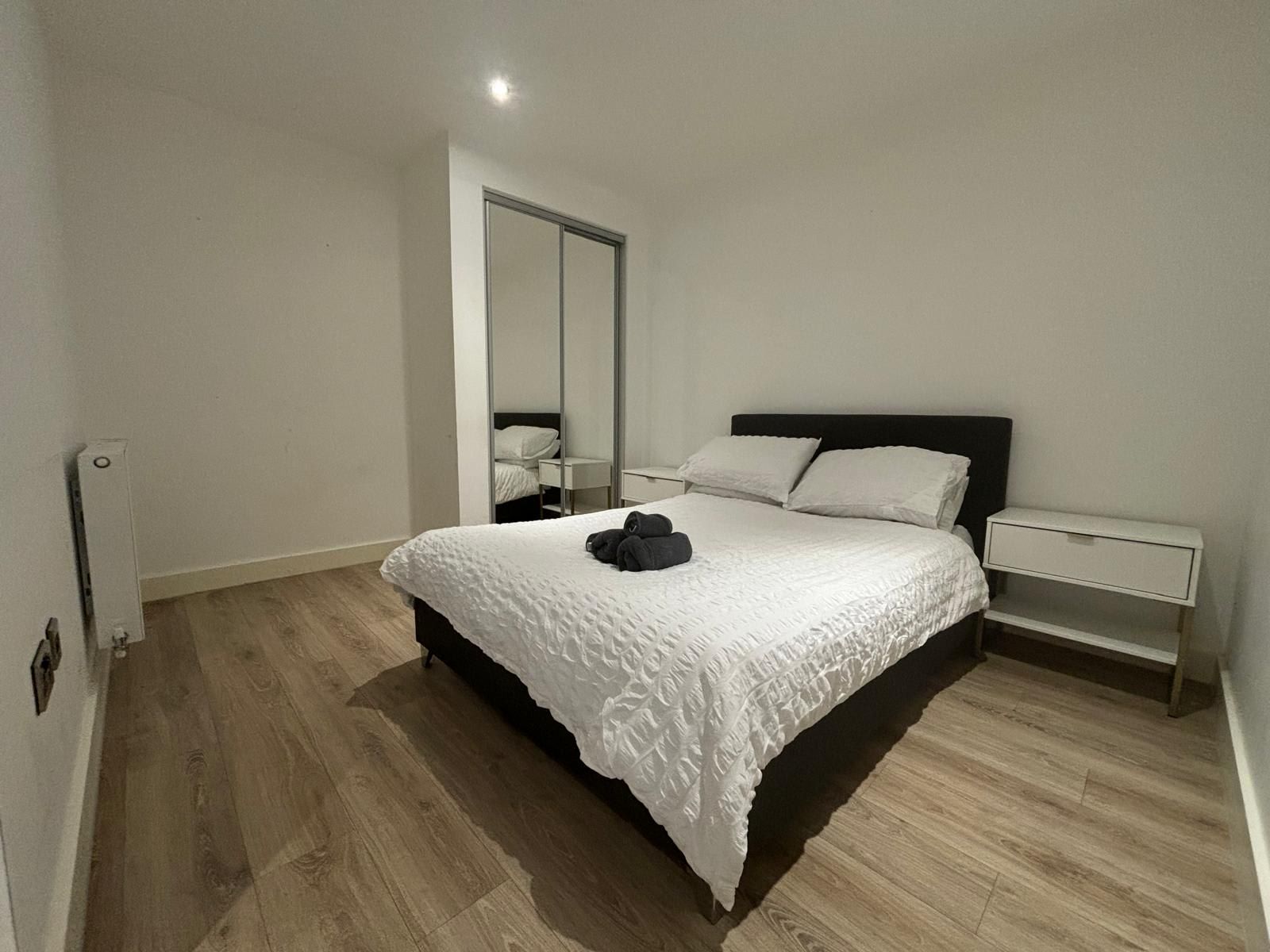 Une chambre à coucher avec un grand lit, une table de chevet, un miroir et une armoire.