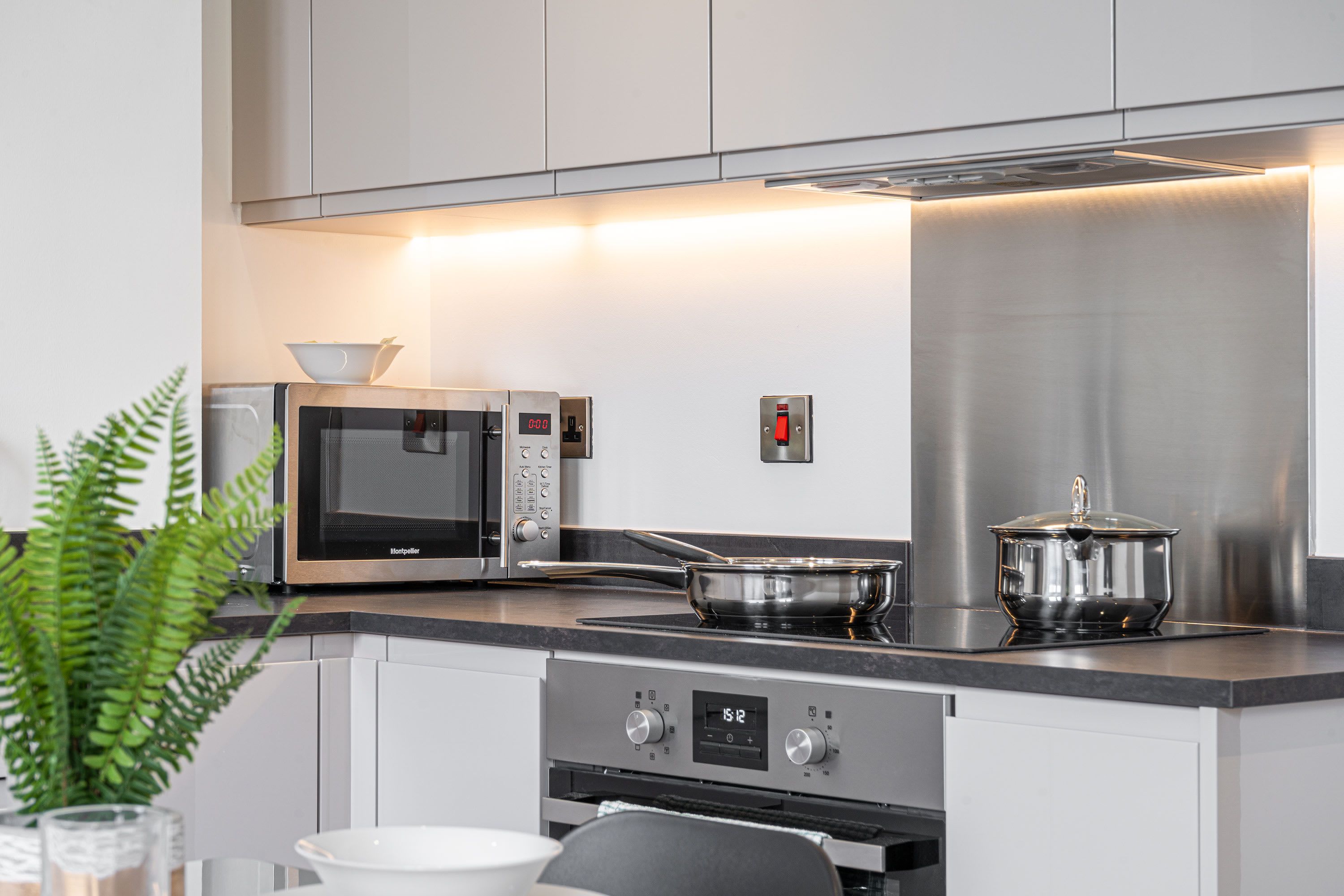 A modern kitchen with stainless steel appliances, a microwave, an oven, and a pot on the stove.