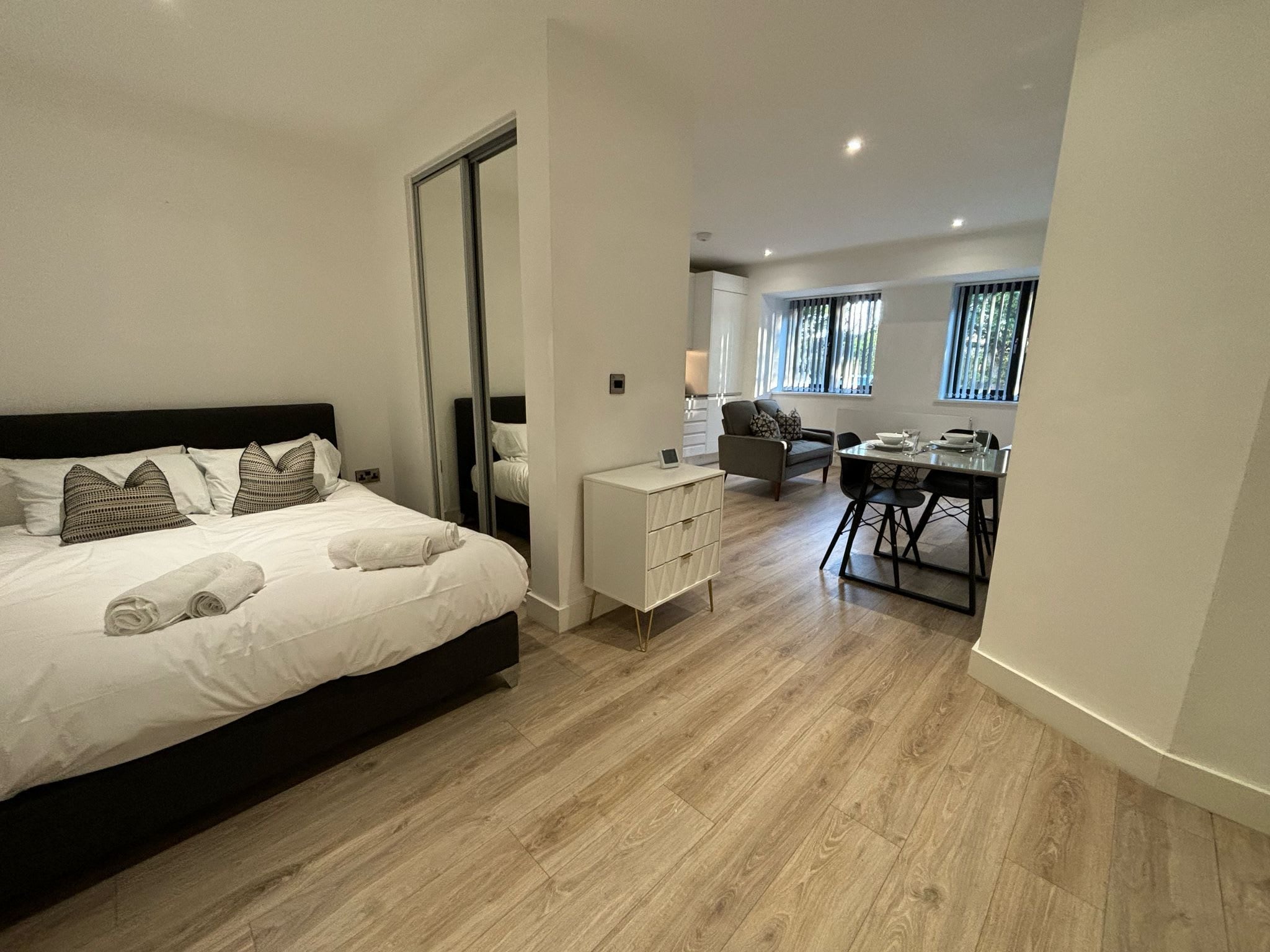 A modern bedroom with a large bed, a small desk, and a dining area.