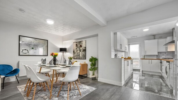 A modern kitchen with white cabinets, a wooden countertop, and a stainless steel range hood.