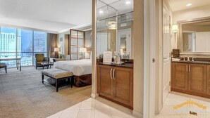 A hotel room with a large bed, a desk, a chair, and a view of the city through large windows. - Relaxing Studio | King Bed, Jacuzzi & Strip View (Las Vegas)