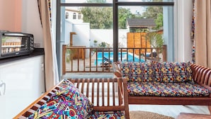 A balcony with a pool, a sofa with colorful cushions, and a microwave on a counter. - Mimea Boutique villa  (Jambiani)