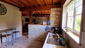 A kitchen with a stone island, a sink, and a bar area with stools. - La Grange, gîte between land and sea. (Verlincthun)