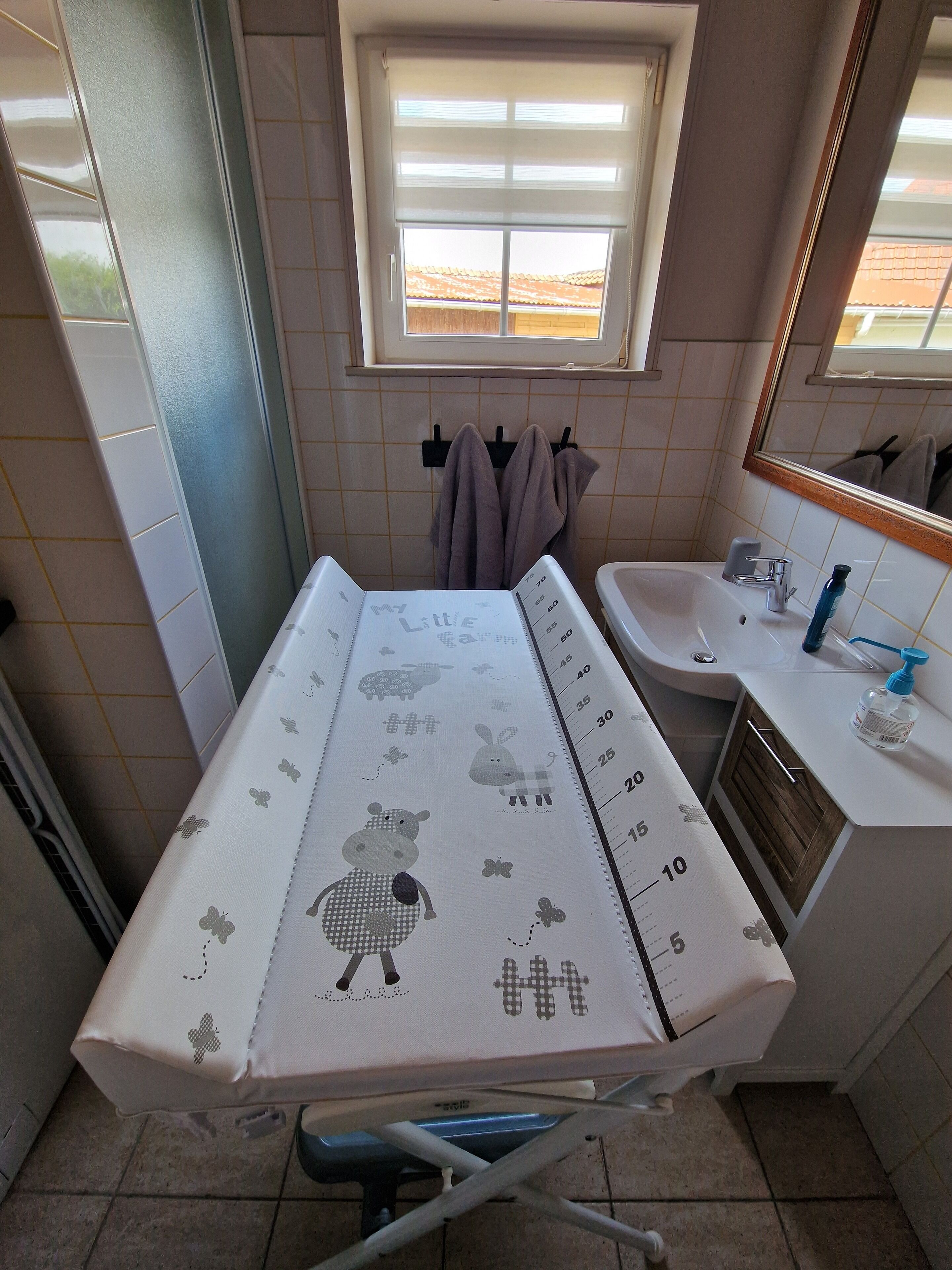 A bathroom with a white sink, a mirror, and a window with blinds.
