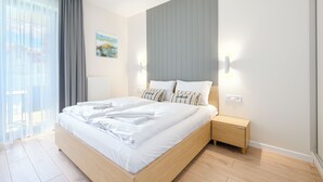 Une chambre à coucher moderne avec un grand lit, une table de chevet, un radiateur et une fenêtre avec des rideaux.