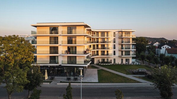 A multi-story hotel with balconies, outdoor seating, and a landscaped courtyard. - Sun & Snow, Euronia (Miedzyzdroje)