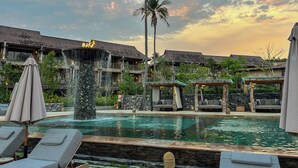A resort with a swimming pool, lounge chairs, a waterfall feature, and traditional architecture. - Dinso Resort & Villas Ko Chang, Vignette Collection by IHG (Ko Chang)