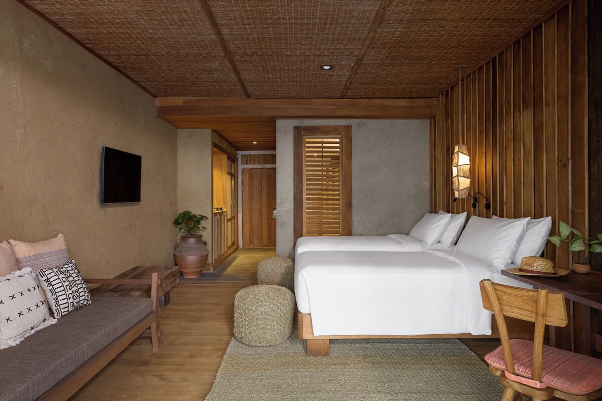 A hotel room with a bed, a sofa, a chair, a desk, and a television.