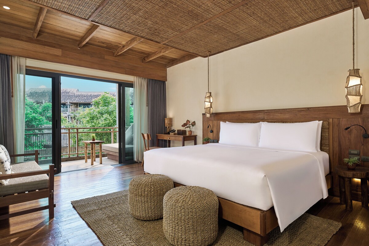 Una habitación de hotel con una cama grande, un balcón con vistas y techo de madera.