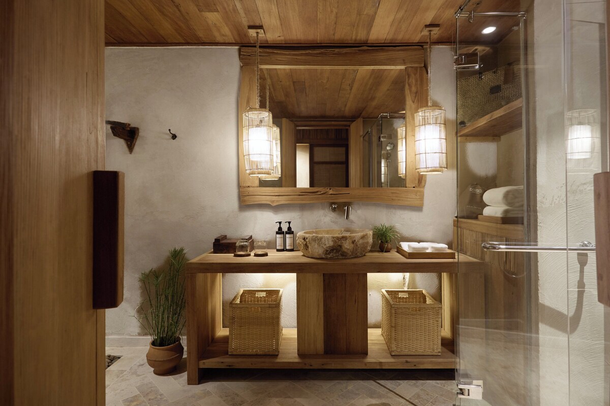 A wooden vanity with a large mirror, two sconces, and a sink.