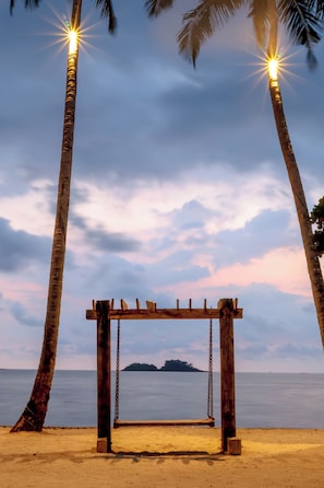 A wooden swing set on a sandy beach with palm trees and a calm sea in the background. - Dinso Resort & Villas Ko Chang, Vignette Collection by IHG (Ko Chang)