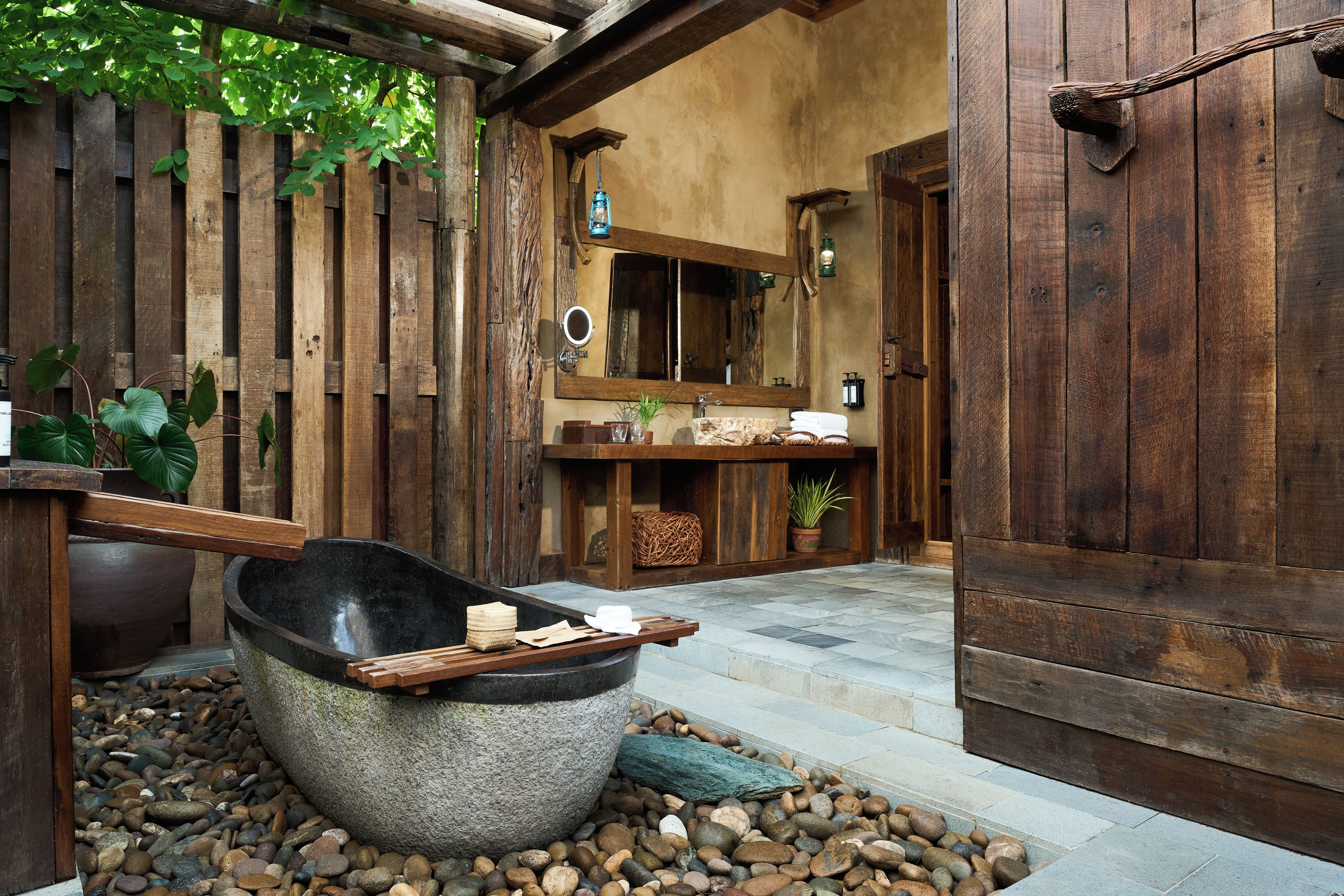 Une salle de bain rustique avec un lavabo en pierre, des murs en bois et un miroir.