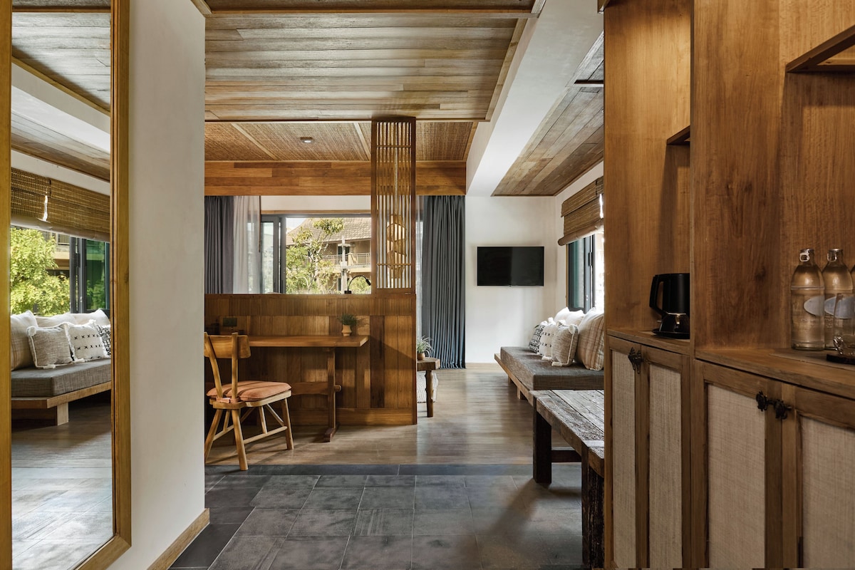 Ein modernes Interieur mit Holzbalkendecke, einem Essbereich mit Tisch und Stühlen sowie einer Sitzecke mit Kissen.